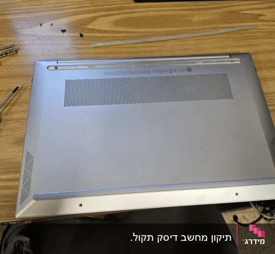 מחשב נייד עם מברג על שולחן עץ